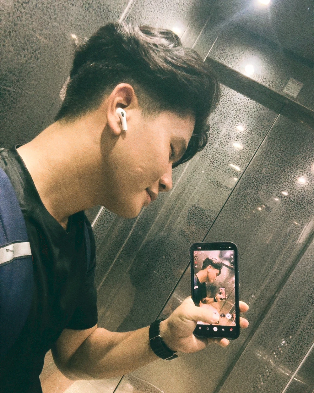 Tenzy taking a mirror photograph in an elevator, holding his phone